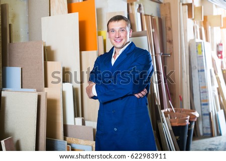 professional workman standing with plywood pieces in picture framing workshop
