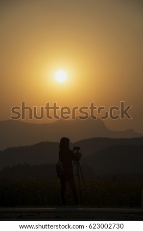 Silhouette woman photographer at sunset, person taking a photo landscape at the high moutain
