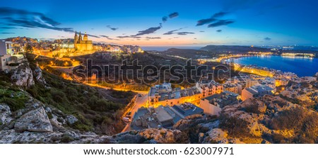 Il-Mellieha, Malta - Beautiful panoramic skyline view of Mellieha town after sunset with Paris Church and Mellieha beach at background with blue sky and clouds