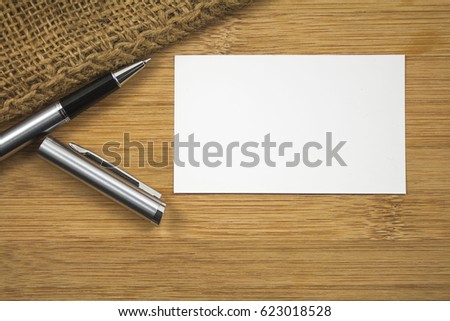 Pen and business card over the wooden board.