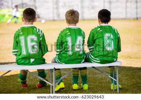 Kids Soccer Team. Youth Soccer Coaching Picture. Soccer Practice Match and Game Day. Young Boys Substitute Players Sitting on Bench and Watching Youth Soccer Training Match