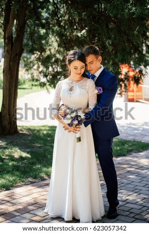 Bride and groom hugs in the park. Groom embraces the bride. Wedding couple in love at wedding day