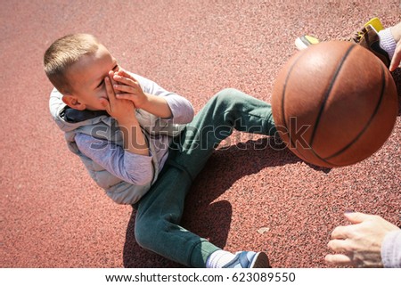 Father wit his son sitting on the basket ball court an playing.