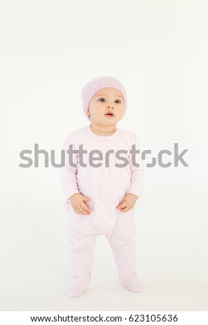 Picture of cute little baby wearing hat standing on floor isolated over white background. Looking aside.