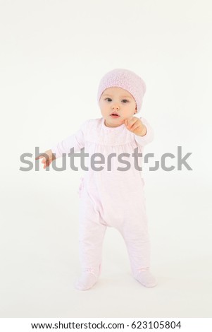 Picture of cute little baby wearing hat standing on floor isolated over white background. Looking at camera.
