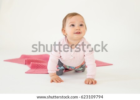 Picture of pretty cute baby girl sitting on floor isolated over white background. Looking aside.
