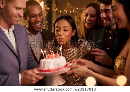 Woman Blowing Out Candles On Birthday Cake