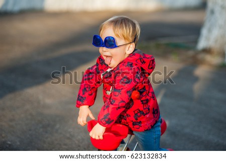 An active little boy walks in the park, skates on a scooter, plays, curves with sunglasses