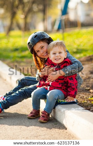 A girl with a boy on a walk in the park, brother and sister laughing