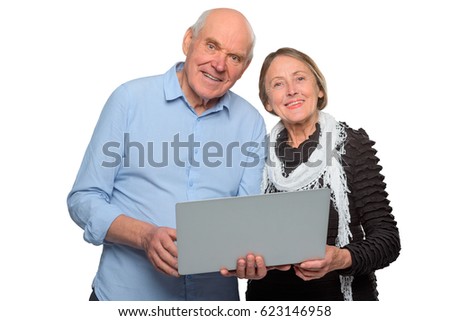 Studio shot of two happy old people. Two pensioners hold gray notebook in hands and study to work with it. Dressed in casual clothes couple looks straight at the camera.
