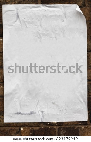 Blank poster texture, crumpled, creased curled at the edges pasted on to a brick wall.