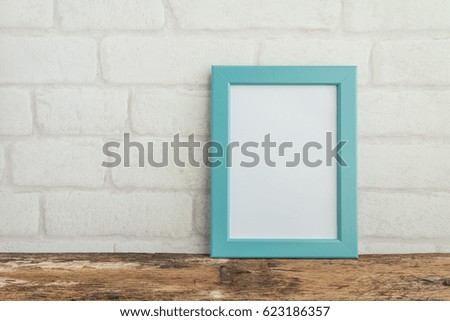 Blue photo frame on old wooden table with white brick wallpaper background