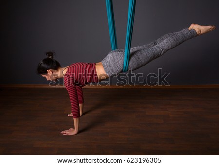 young beautiful woman doing fly yoga. Sitting in hammock with namaste gesture. Wellness concept.