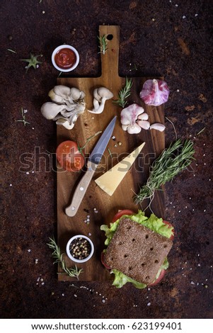 Healthy vegetable sandwich in rye bun with ingredients on wooden background. Top view.