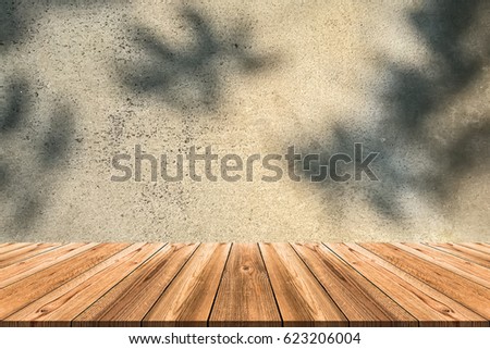 Wooden board empty table in front of blurred background. Perspective crack old concrete wall with shadow of tree can be used for display or montage your products