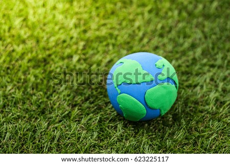 Globe made from clay lies on green grass. Concept - Earth Day.