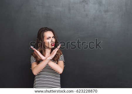 Displeased woman showing stop gesture and looking at the camera over black background