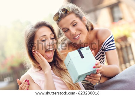 A picture of two girl friends making a surprise birthday present
