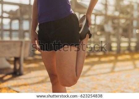 Sports woman stretching her leg after running outdoors.