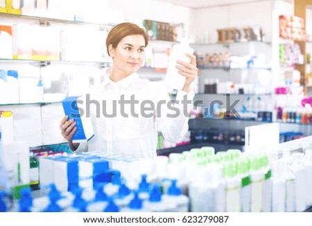 Young female customer is browsing rows of body care products in pharmacy. 