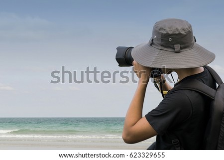 Young man Photographer is taking a still image near the sea in the Afternoon. 