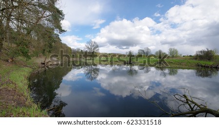 River bend with reflection of cloudy sky. Warta river in Poland.