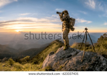 Blur Young man with backpack taking a photo on the top of mountains, sunset