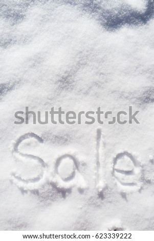 Word SALE written vertically in the snow on a sunny spring day.