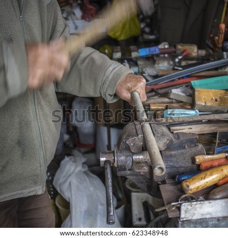 Metalworker works metal with hammer, candid photography