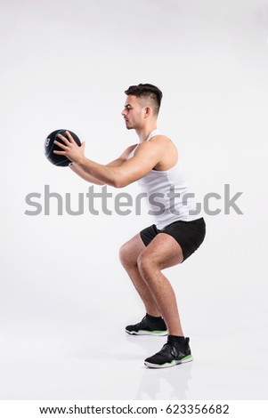 Handsome fitness man holding medicine ball, studio shot.