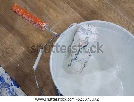 paint roller and 
white color in paint bucket.