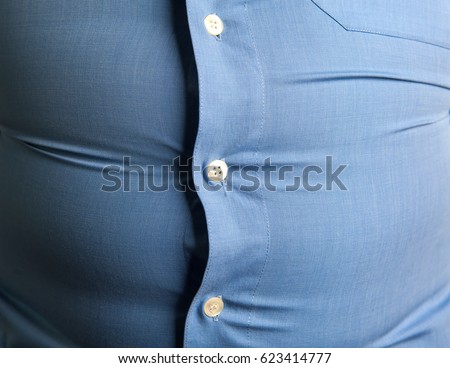 man with overweight. symbolic photo for beer belly, unsuccessful dieting and eating the wrong foods. Weight loss concept. Tight shirt. Royalty-Free Stock Photo #623414777