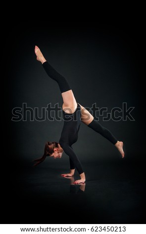 woman gymnast showing athletic skill against dark background
