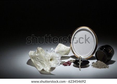 black urn with white tape,white chrysanthemum, rosary for sympathy card on background
