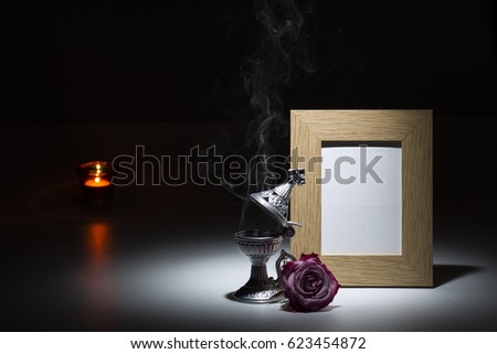 natural wooden picture frame with thurible, pink rose and candle light on dark background