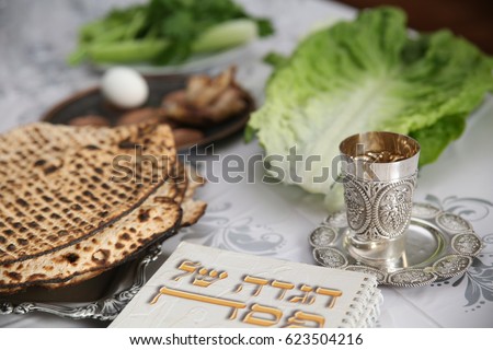 Table Ready For Traditional Seder Ritual during the Jewish holiday of Passover.
. (Kiddush cup, haggada, matzos, lettuce, an arm) Royalty-Free Stock Photo #623504216