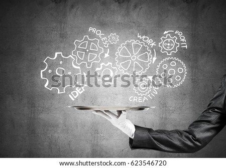 Butler holding metal tray with teamwork concept against concrete background