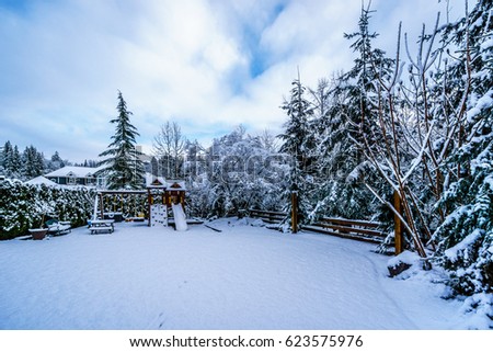 Snow covered Play Ground in the Fraser Valley of British Columbia, Canada on a cold winter day and with snow covered trees and lawn Royalty-Free Stock Photo #623575976