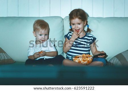Children brother and sister watching TV in the evening

