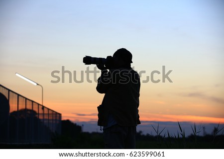silhouette A man photographer on twilight sky background, A tourist man  taking pictures with a camera, professional photography standing take a photo 