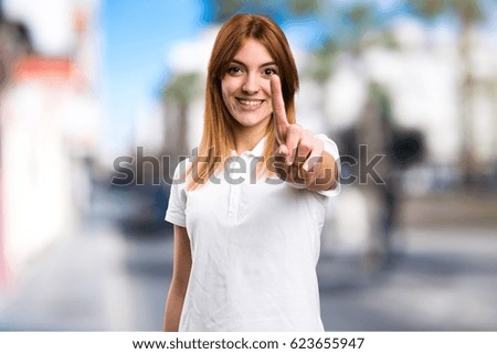 Beautiful young girl counting one on unfocused background