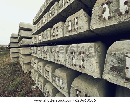 Sleepers stock in railway depot. New concrete railway ties stored for reconstruction of old railway station. Old houses  in background