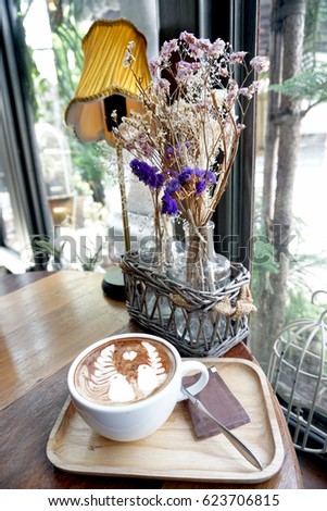 Good morning coffee cup - a cup of hot mocha with latte art on wooden table and dried flower.