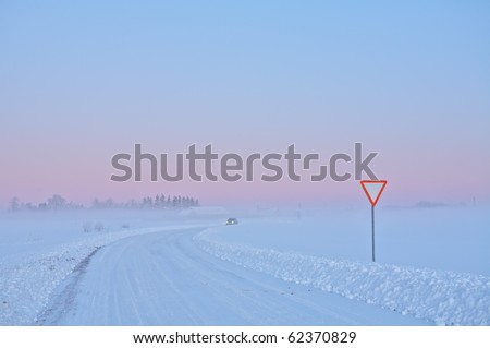 Picture of winter road with road sign and car in cold climate on sunset
