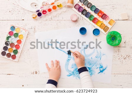 Top view on child's hands drawing. Colorful picture made by a toddler boy. Creative ideas and learning. Education concept.