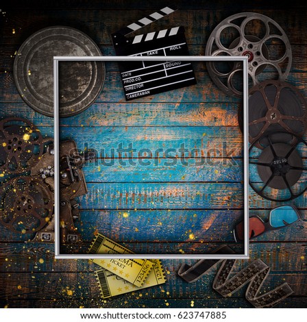 Cinema concept of vintage film reels, clapperboard and other tools on old wooden background.