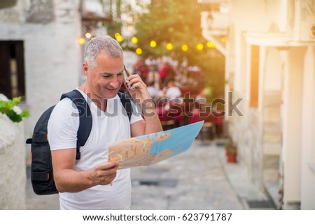 tourist looking at the map on the street of european city, travel to Europe. bright orange sunset light, freedom and active lifestyle concept. Man with backpack using and looking at map