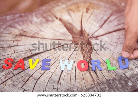 Colorful wooden alphabet "SAVE WORLD" on tree stump and blur of park background. Love tree or save world concept