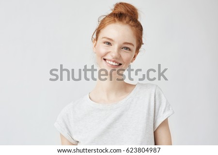Headshot Portrait of happy ginger girl with freckles smiling looking at camera. White background. Royalty-Free Stock Photo #623804987