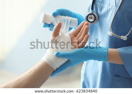 Medical assistant applying bandage onto patient's hand in clinic, closeup Royalty-Free Stock Photo #623834840